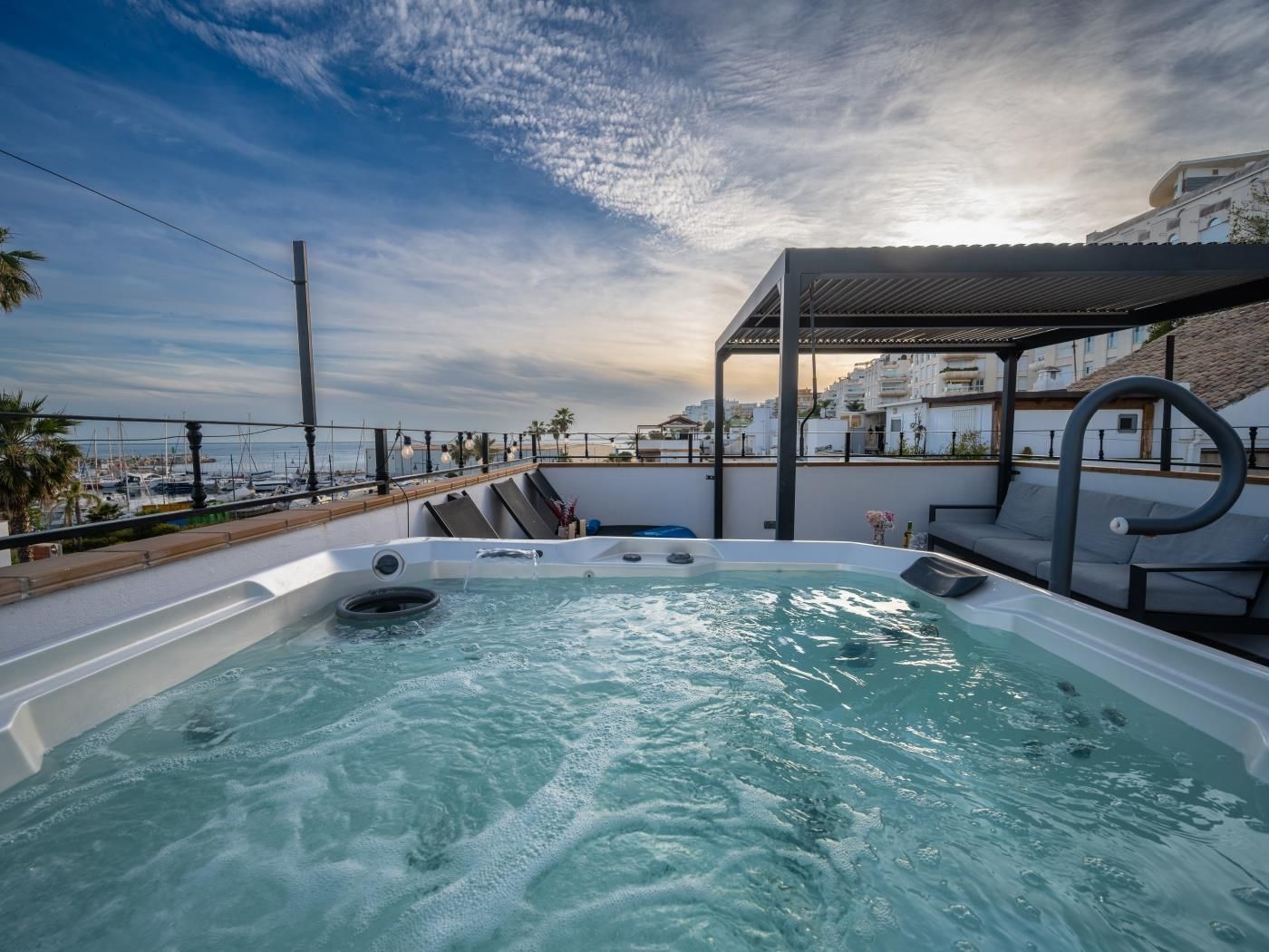 Rooftop jacuzzi on the solarium terrace with views over Marbella's marina and the Mediterranean at dusk