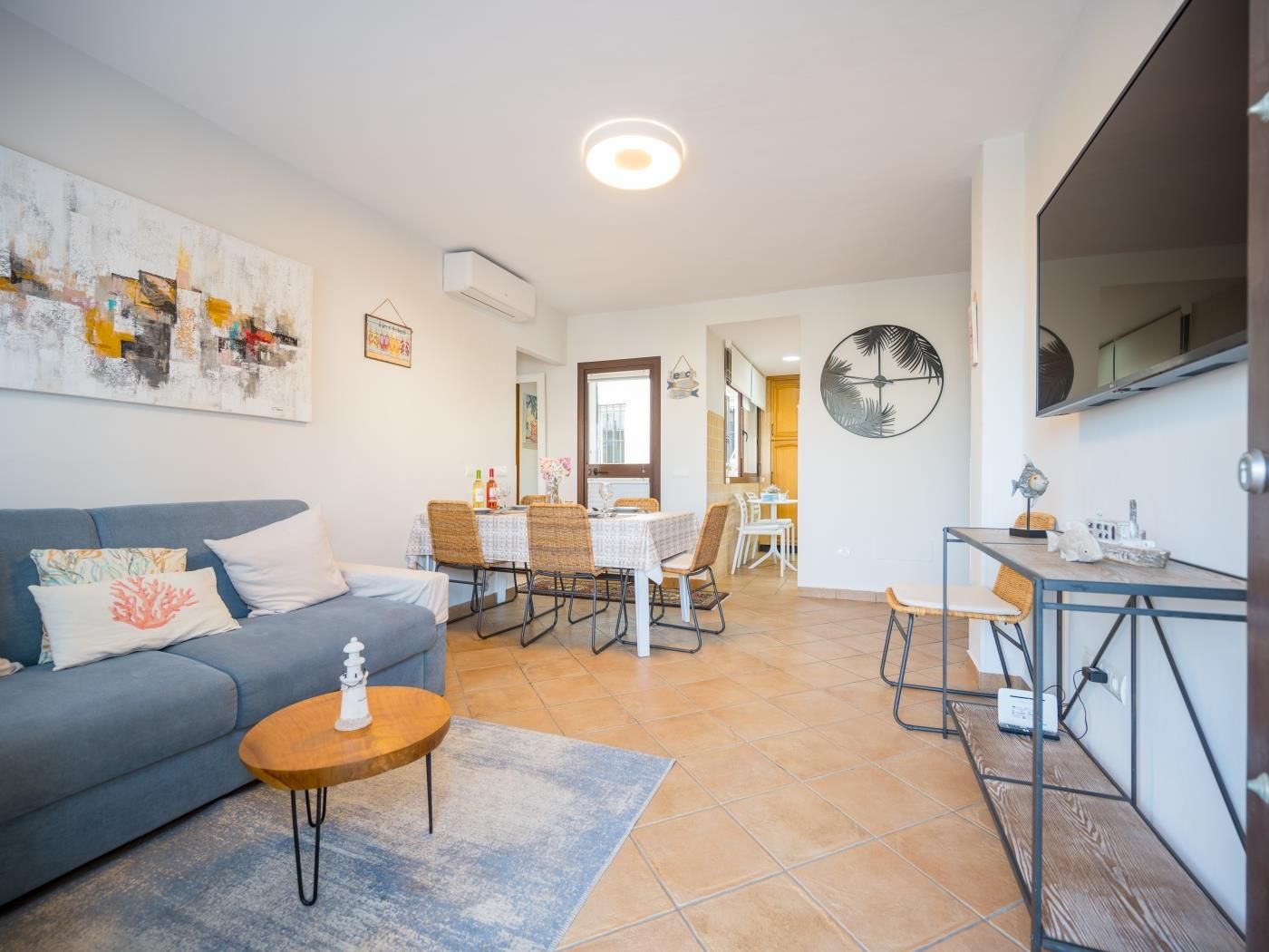 Bright lounge with sofa, wall-mounted TV and dining area in the Marbella port townhouse