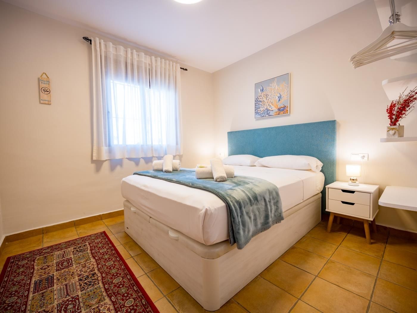 Double bedroom with teal headboard and marine-themed artwork in Casa del Puerto