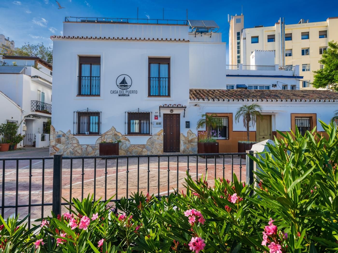 Whitewashed façade of the Casa del Puerto townhouse with pink oleanders in bloom, steps from Marbella's marina